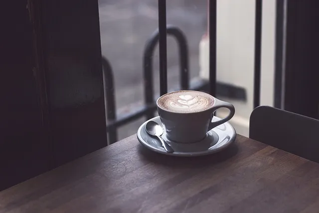 Filiżanka kawy latte z pianką na drewnianym stoliku
